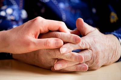 Pair of clasped hands on a table being held by a single hand