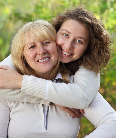 two women embracing in a green field