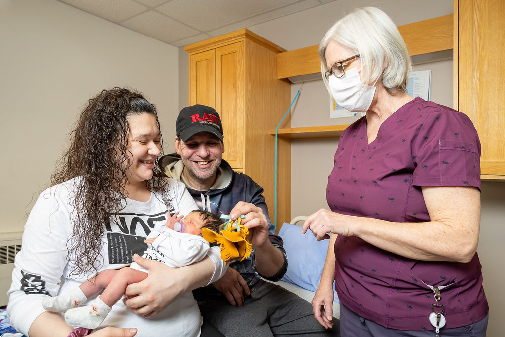 Nurse presenting couple with new baby with a small pair of indigenous moccasins