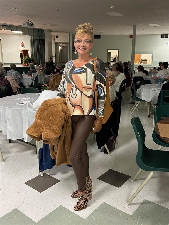 Photo of a woman in a hall with tables posing wearing an outfit from the gift shop 